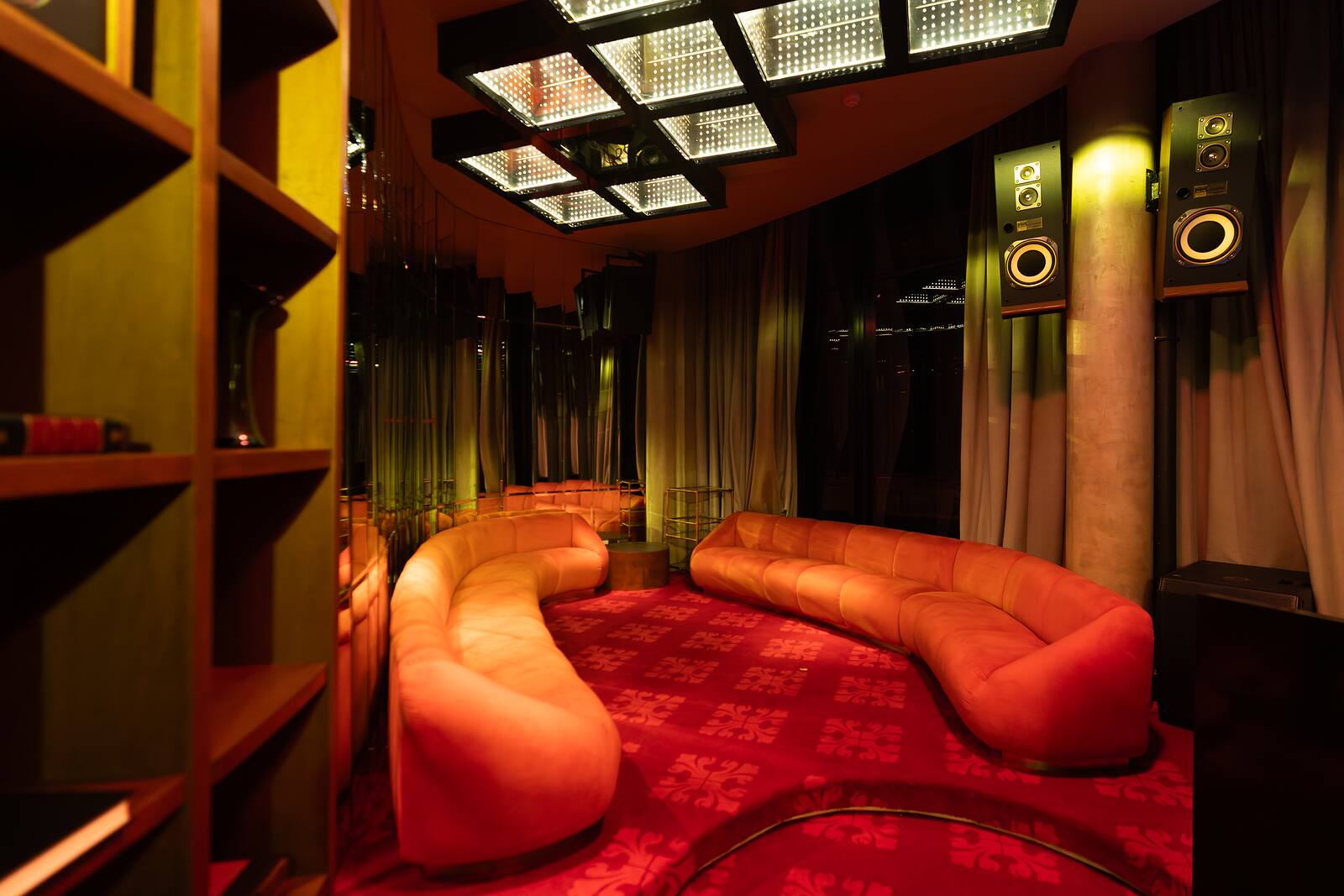 Loft de Caramelo con sillón curvo y biblioteca iluminada.